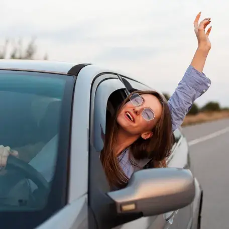 mulher dentro do carro gritando de alegria com braço para fora do carro